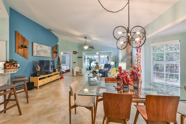 tiled dining area featuring ceiling fan with notable chandelier, lofted ceiling, a healthy amount of sunlight, and a textured ceiling