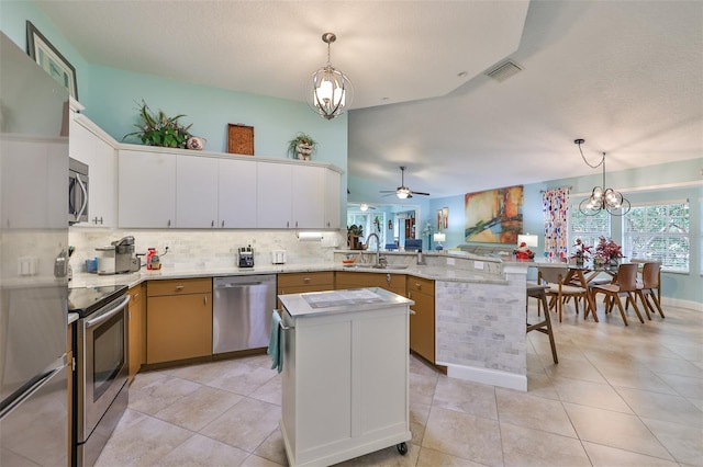 kitchen featuring ceiling fan with notable chandelier, appliances with stainless steel finishes, kitchen peninsula, and decorative light fixtures