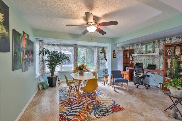 interior space with a wealth of natural light, ceiling fan, light tile patterned floors, and a textured ceiling