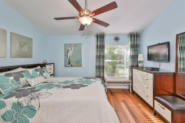 bedroom with a textured ceiling, ceiling fan, lofted ceiling, and light hardwood / wood-style floors