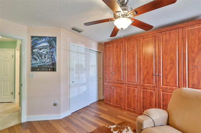 unfurnished room with light wood-type flooring, a textured ceiling, and ceiling fan