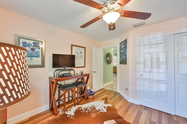 office space with light wood-type flooring, ceiling fan, and a textured ceiling