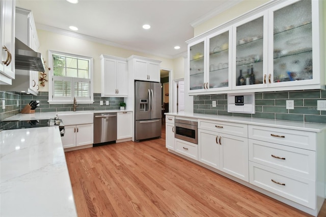 kitchen featuring backsplash, stainless steel appliances, light hardwood / wood-style floors, wall chimney range hood, and white cabinets