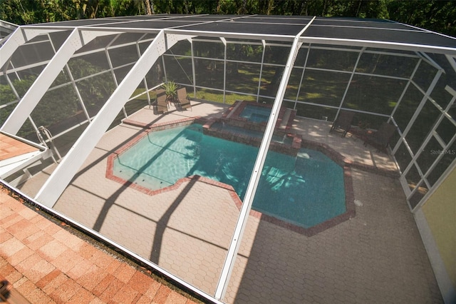 outdoor pool featuring glass enclosure, an in ground hot tub, and a patio