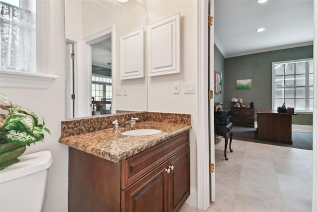 bathroom with baseboards, toilet, crown molding, vanity, and recessed lighting