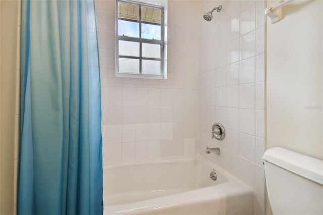 bathroom with toilet and shower / bathtub combination with curtain