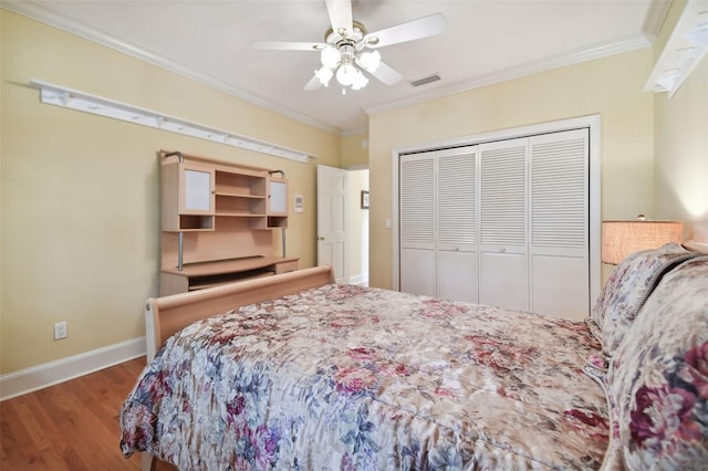 bedroom with a closet, visible vents, ornamental molding, wood finished floors, and baseboards