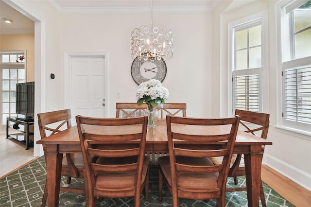 dining space with baseboards, ornamental molding, a chandelier, and wood finished floors