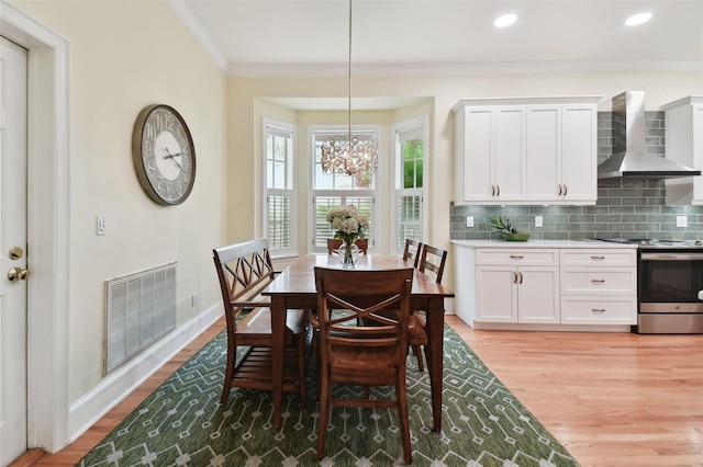 dining space featuring light wood finished floors, ornamental molding, visible vents, and baseboards