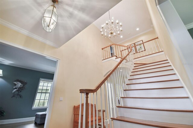 staircase featuring wood-type flooring, ornamental molding, and a chandelier