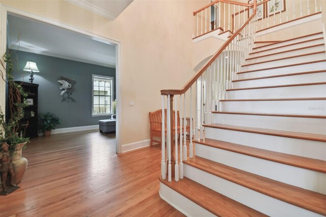 stairway with crown molding and wood-type flooring