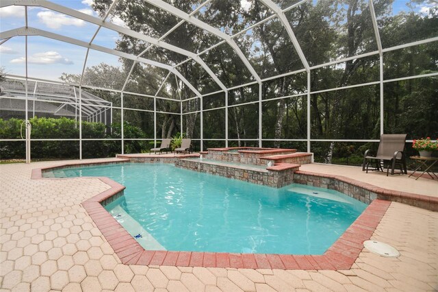 pool featuring a lanai, a patio, and an in ground hot tub