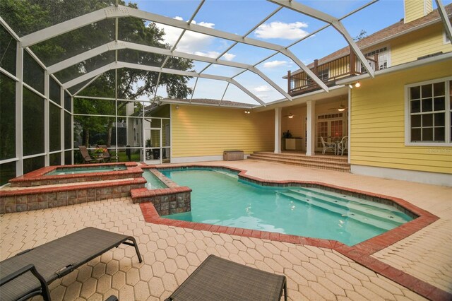 view of pool with a patio, glass enclosure, and an in ground hot tub