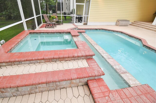 view of swimming pool with an in ground hot tub, glass enclosure, and a patio