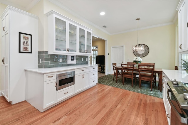 kitchen with white cabinetry, glass insert cabinets, light countertops, and decorative light fixtures