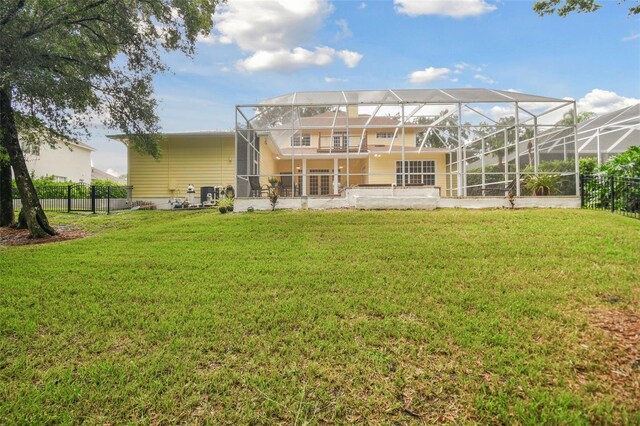 back of property with a lawn and glass enclosure