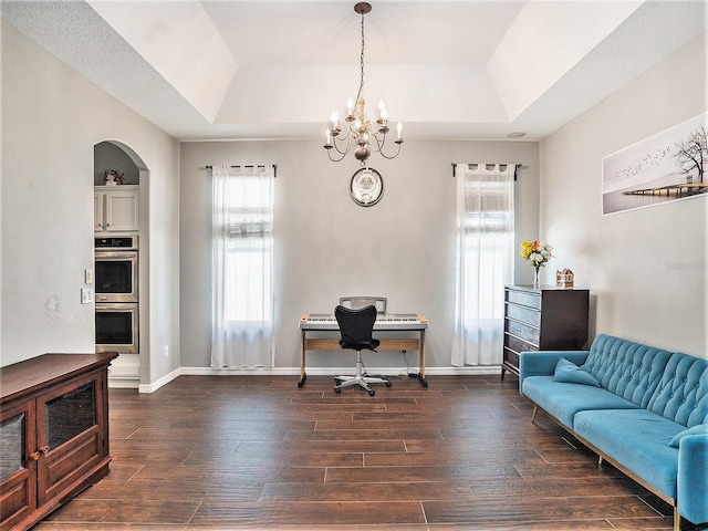 home office with a tray ceiling, dark wood-type flooring, and an inviting chandelier