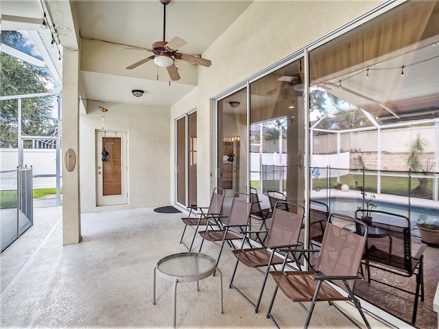 view of patio / terrace featuring ceiling fan and glass enclosure