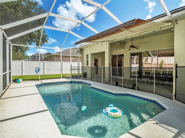 view of swimming pool featuring glass enclosure, ceiling fan, and a patio area