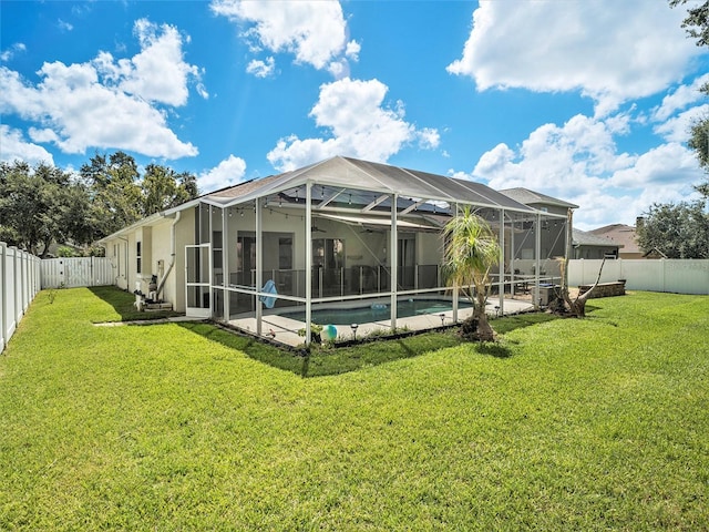 back of house featuring glass enclosure, a fenced in pool, a yard, and a patio