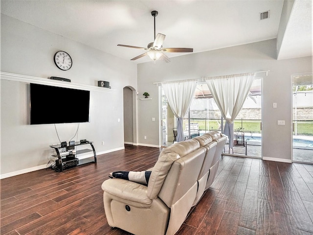 living room with plenty of natural light, ceiling fan, vaulted ceiling, and dark wood-type flooring