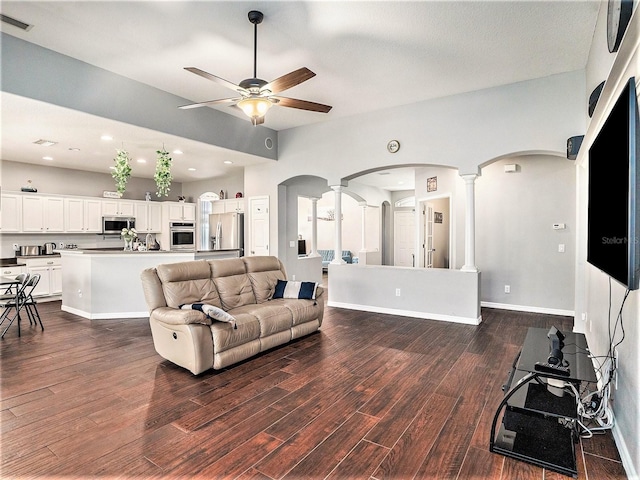 living room featuring dark wood-type flooring, ornate columns, and ceiling fan