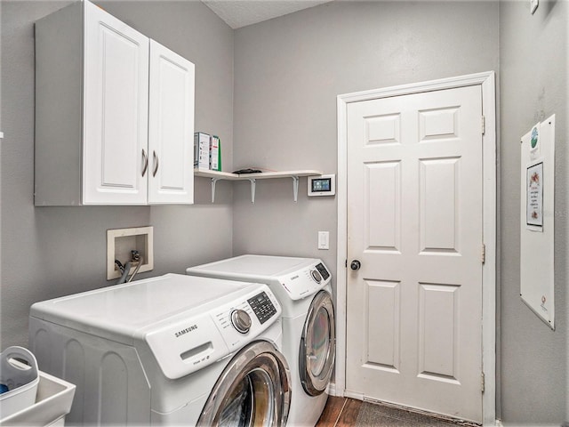 clothes washing area featuring cabinets, washing machine and dryer, and dark hardwood / wood-style flooring