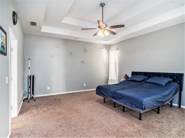 bedroom with a tray ceiling, carpet, and ceiling fan