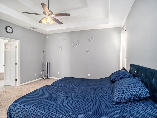 bedroom with a tray ceiling, light carpet, and ceiling fan