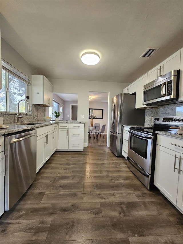 3763 Dartmouth Ave N, Saint Petersburg, FL 33713 - kitchen featuring stainless steel appliances, backsplash, white cabinets, and light stone counters