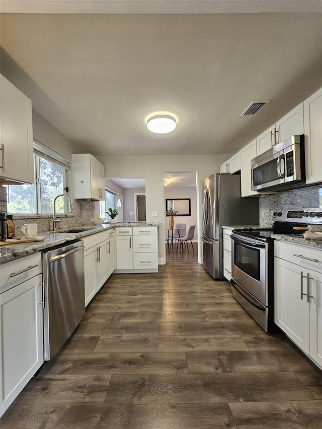 3763 Dartmouth Ave N, Saint Petersburg, FL 33713 - kitchen featuring appliances with stainless steel finishes, a sink, white cabinetry, and decorative backsplash