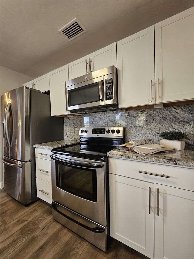 3763 Dartmouth Ave N, Saint Petersburg, FL 33713 - kitchen with appliances with stainless steel finishes, dark wood-style flooring, white cabinetry, decorative backsplash, and light stone counters