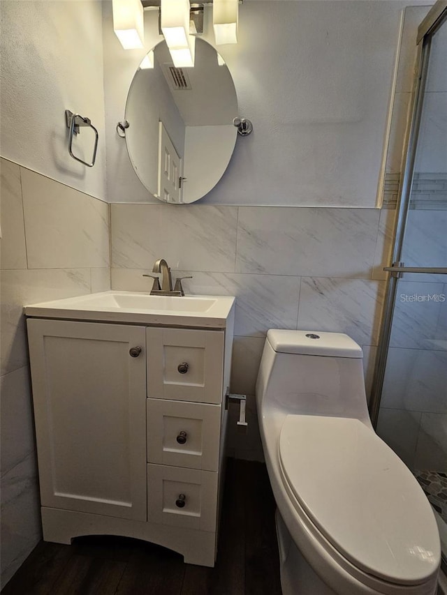 3763 Dartmouth Ave N, Saint Petersburg, FL 33713 - bathroom with tile walls, toilet, vanity, a shower stall, and wood finished floors