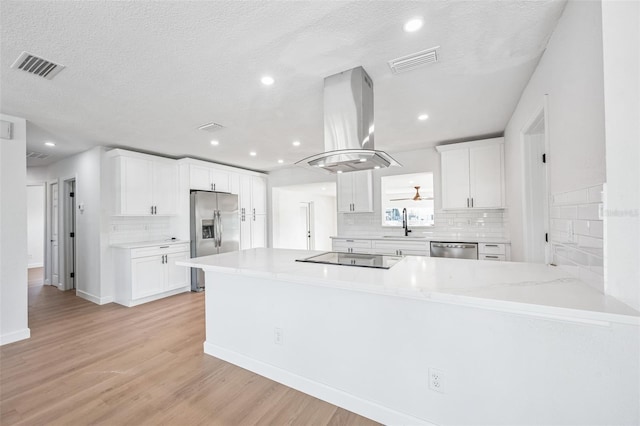 kitchen with light wood-style floors, visible vents, island exhaust hood, and appliances with stainless steel finishes