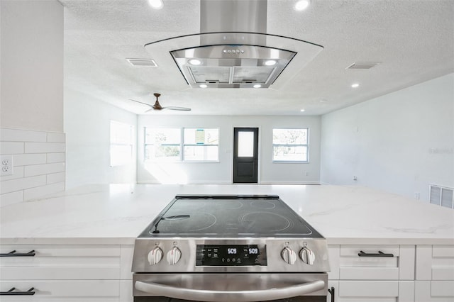 kitchen featuring white cabinetry, visible vents, light stone counters, and stainless steel range with electric cooktop