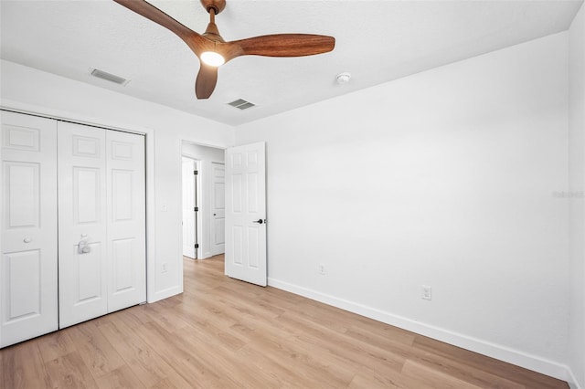 unfurnished bedroom featuring light wood-type flooring, baseboards, visible vents, and a closet