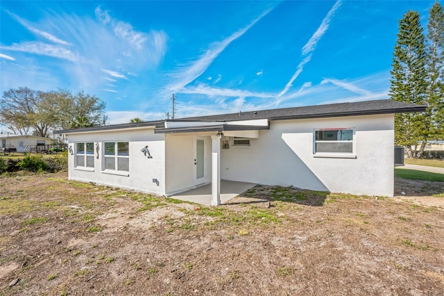 rear view of house featuring stucco siding, an AC wall unit, and a patio