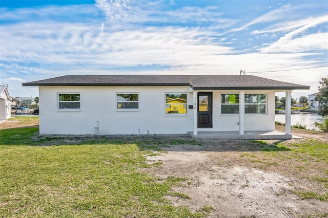 single story home featuring a shingled roof, a front yard, and stucco siding