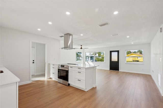 kitchen featuring stainless steel electric range oven, light countertops, extractor fan, and visible vents