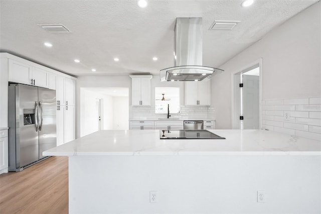 kitchen with stainless steel appliances, visible vents, island range hood, and white cabinetry