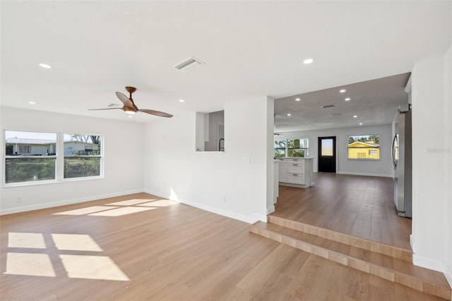 spare room featuring a barn door, recessed lighting, visible vents, baseboards, and light wood-style floors