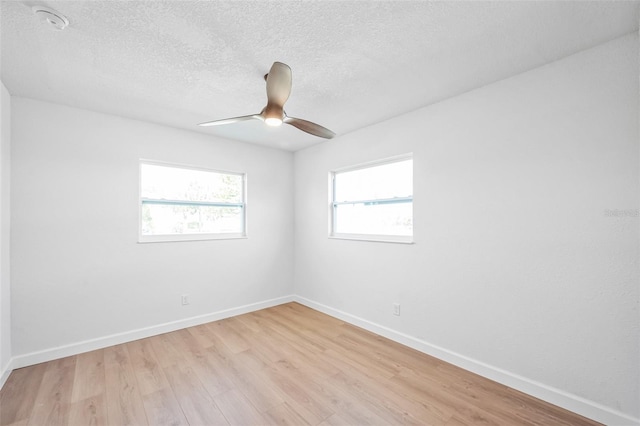 empty room featuring light wood-type flooring, a ceiling fan, baseboards, and a textured ceiling