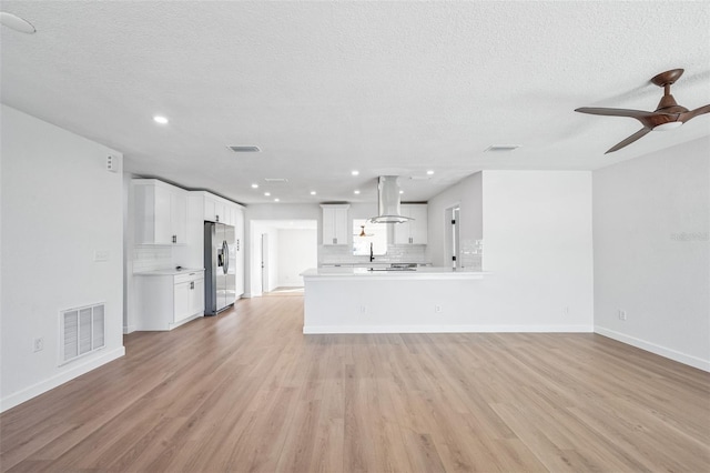 unfurnished living room featuring light wood-type flooring, visible vents, ceiling fan, and baseboards