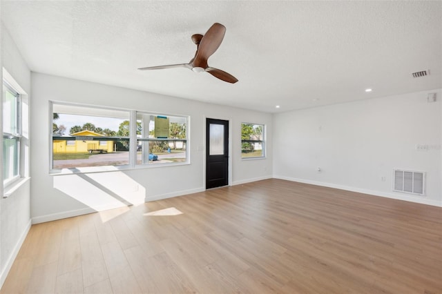 interior space featuring visible vents, a textured ceiling, baseboards, and wood finished floors