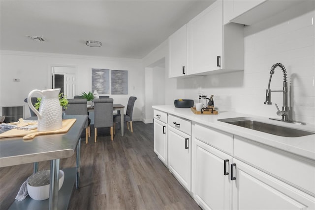 kitchen with sink, dark wood-type flooring, white cabinets, and crown molding