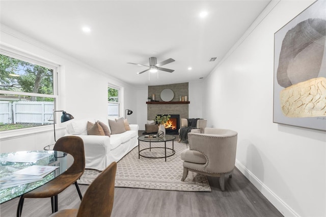 living room with a fireplace, ceiling fan, crown molding, and hardwood / wood-style flooring