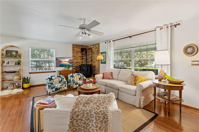 living room featuring hardwood / wood-style floors, plenty of natural light, a wood stove, and ceiling fan