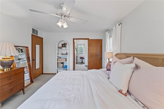 bedroom with ceiling fan, a textured ceiling, and light carpet