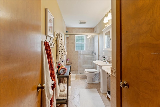 bathroom with tile patterned floors, a shower with shower door, vanity, and toilet