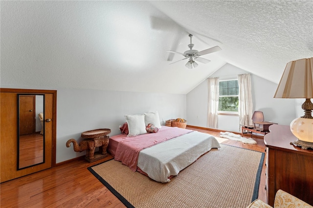 bedroom with hardwood / wood-style flooring, a textured ceiling, lofted ceiling, and ceiling fan